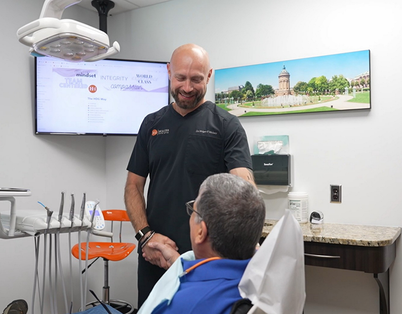 Doctor Holger shaking hands with a man in the dental chair