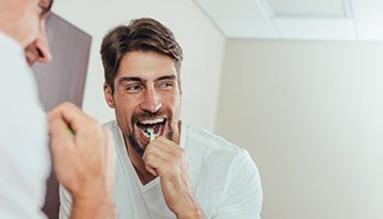 Man smiling while brushing his teeth