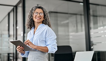 Woman smiling while holding tablet in office