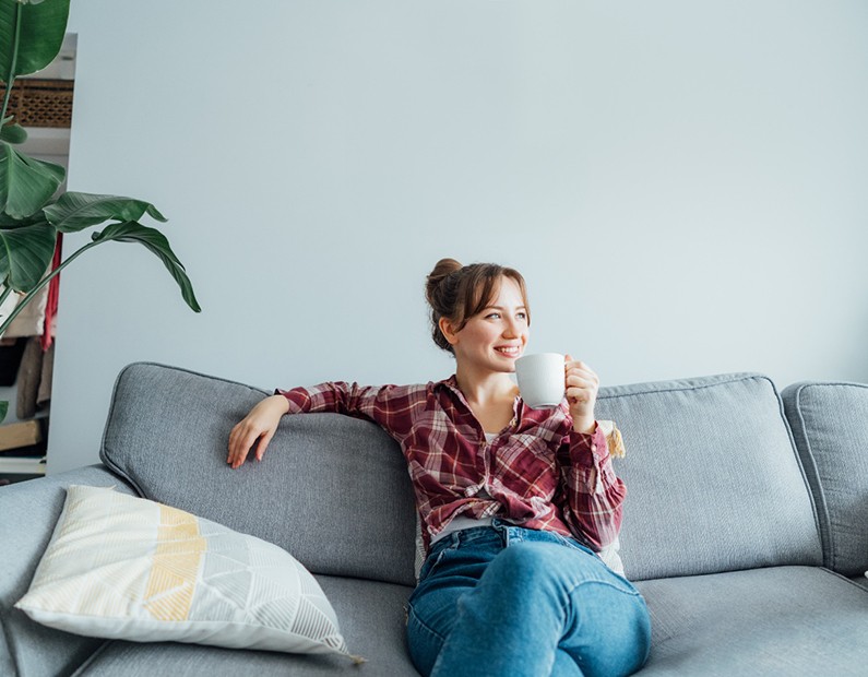 a woman relaxing on a couch and holding a coffee mug