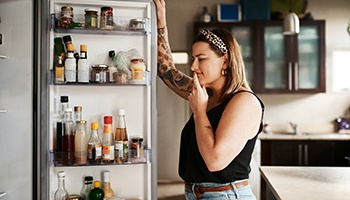 a woman wearing a hairband searching in her refrigerator