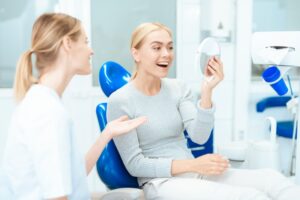 Woman smiling into a mirror after cosmetic dental treatment