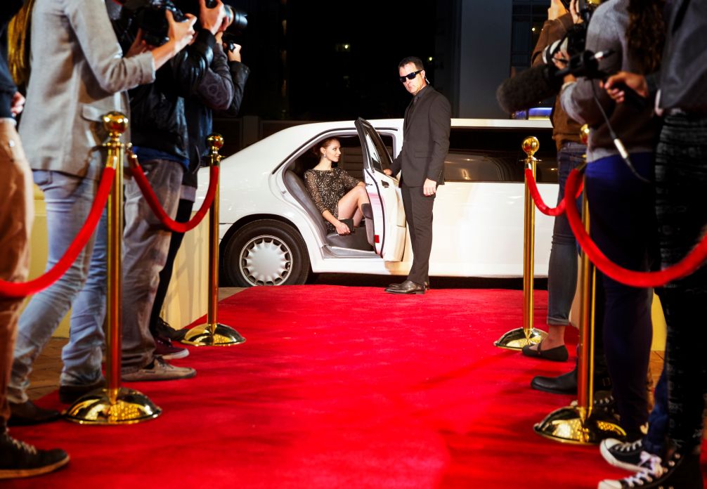 A celebrity arriving at a red-carpet event in a limousine